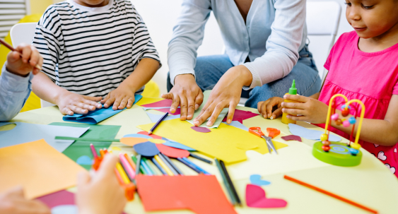Children and teacher doing arts and crafts with colorful paper and supplies