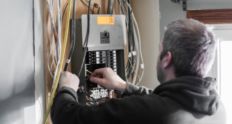 electrician working on adding wiring to fuse box