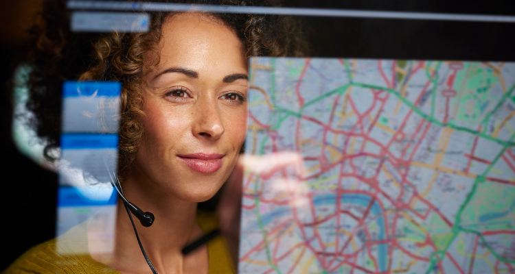 female dispatcher looking at a map and wearing a headset