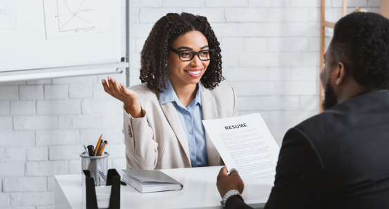female human resource employee interviewing a male with a resume in hand