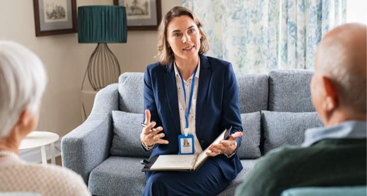 social worker on couch talking to elderly couple