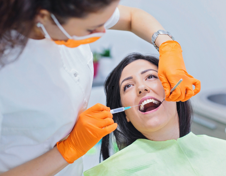 dental assistant giving local anesthesia to patient in chair