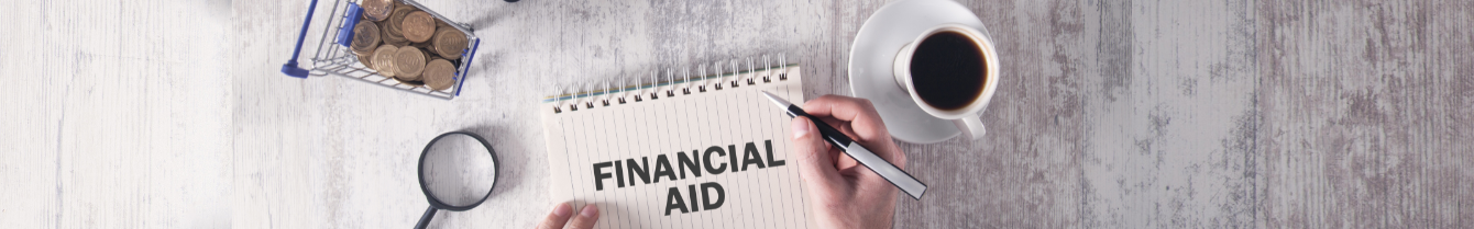 man's hand writing financial aid on notebook with calculator, money and other desk accessories