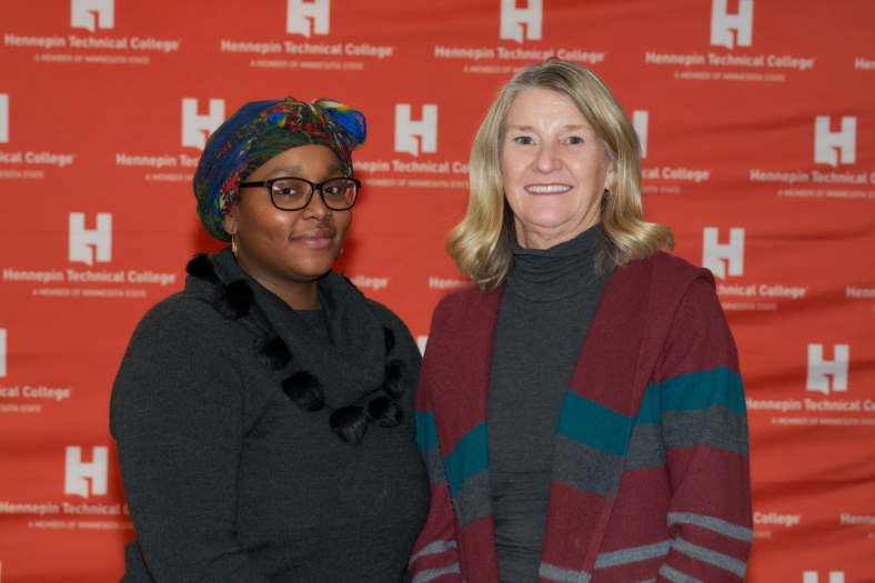 Two women stand in front of the Hennepin Tech background.