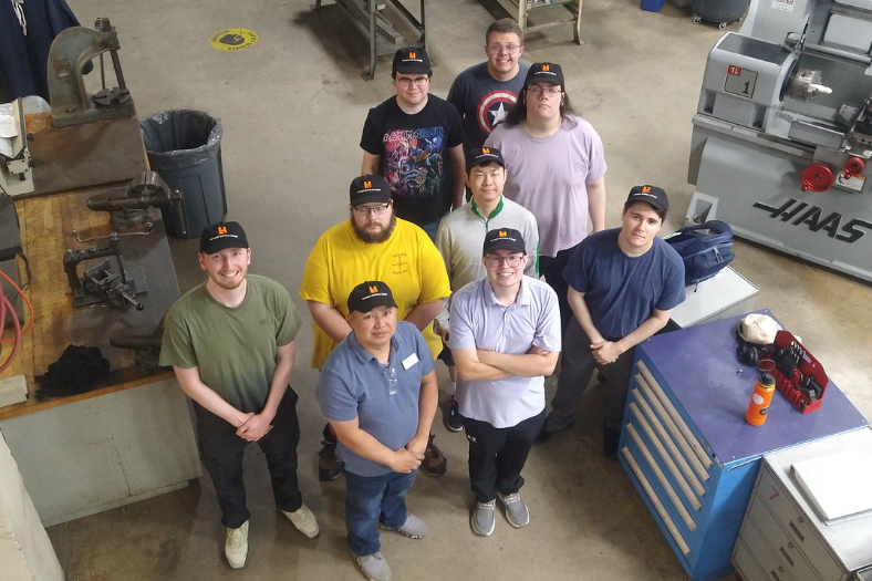 The first cohort of Uniquely Abled Academy students pictured in the Machine Tool Technology lab along side their instructors.