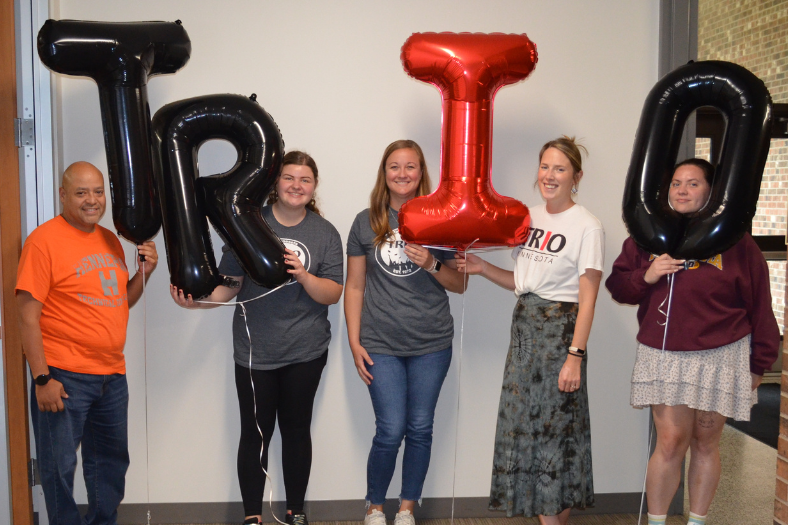 TRIO SSS employees standing in a row holding large balloons the spell out "TRIO"